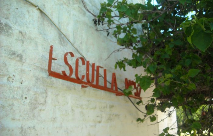 Algunas hojas no cubren el cartel que indica que ah&iacute; funciona una escuela, a orillas del lago.