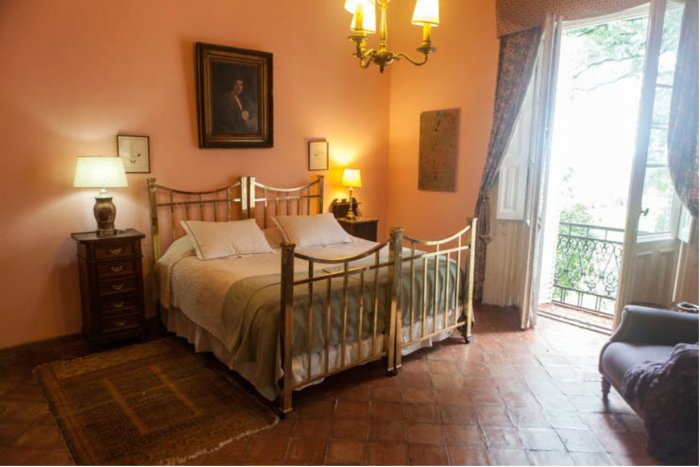 Camas de bronce y baldosones coloniales en una habitaci&oacute;n en Santa C&aacute;ndida.