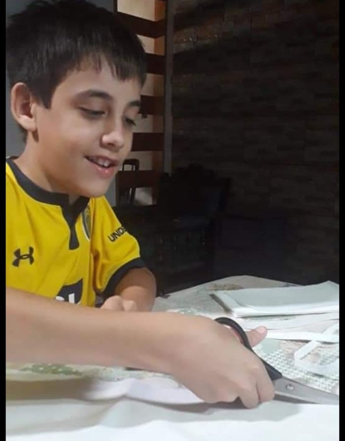 Leonidas es el segundo hijo de Valeria y uno de los que la ayuda a cortar la tela para los barbijos.