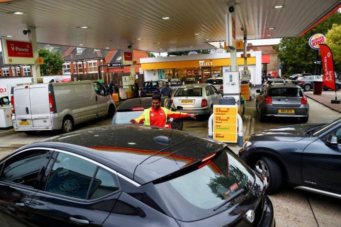 Un empleado guiaba a veh&iacute;culos a la entrada de una gasolinera en Londres / Hannah Mckay (Reuters).