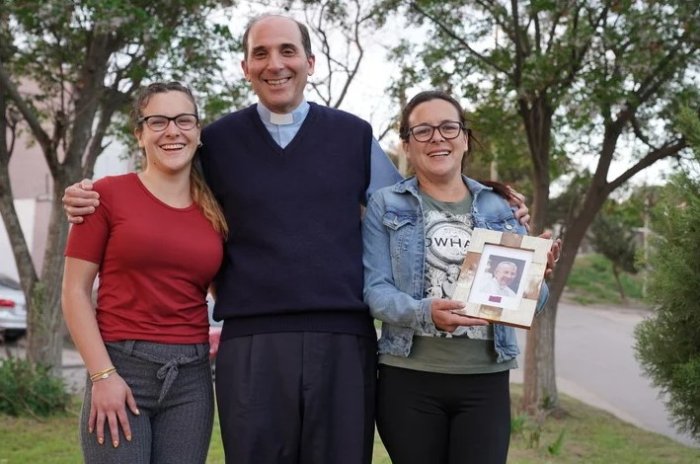 Candela Giarda, el padre Jos&eacute; Dabusti y Roxana, con una foto de Juan Pablo I