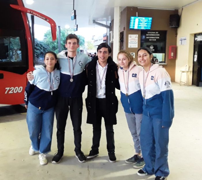 Los 4 estudiantes de Comercio 2 y su asesor, en la terminal de &oacute;mnibus.