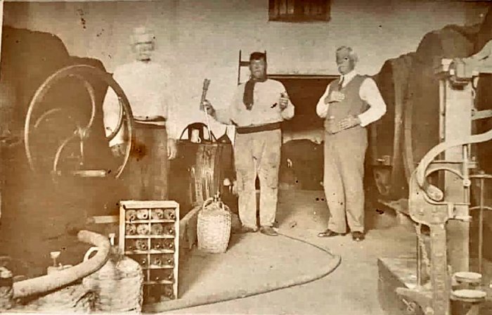 Los tres hermanos Moulins: Francisco, Luis y Carlos en la bodega con toneles, damajuanas, botellas y maquinaria.