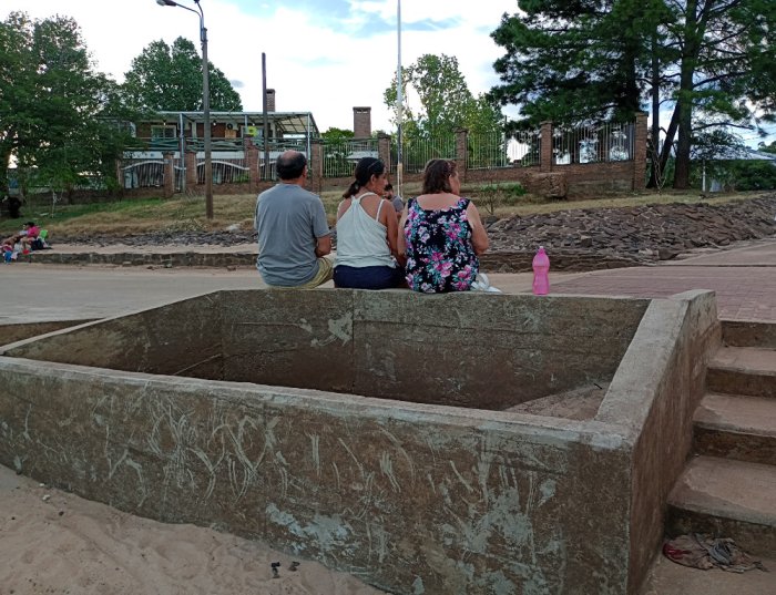 Otros toman mate d&aacute;ndole la espalda al r&iacute;o y mirando la puesta del sol. Las paredes testimonian la creciente.