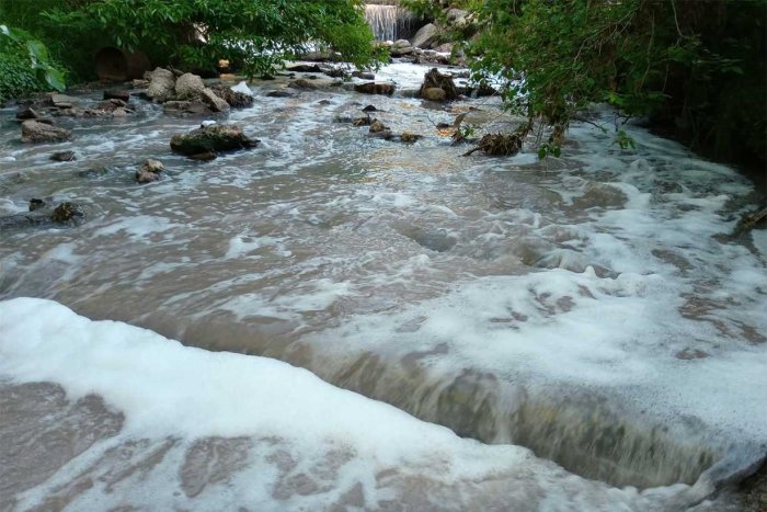 Agua oscura y espumosa en el arroyo Crespo