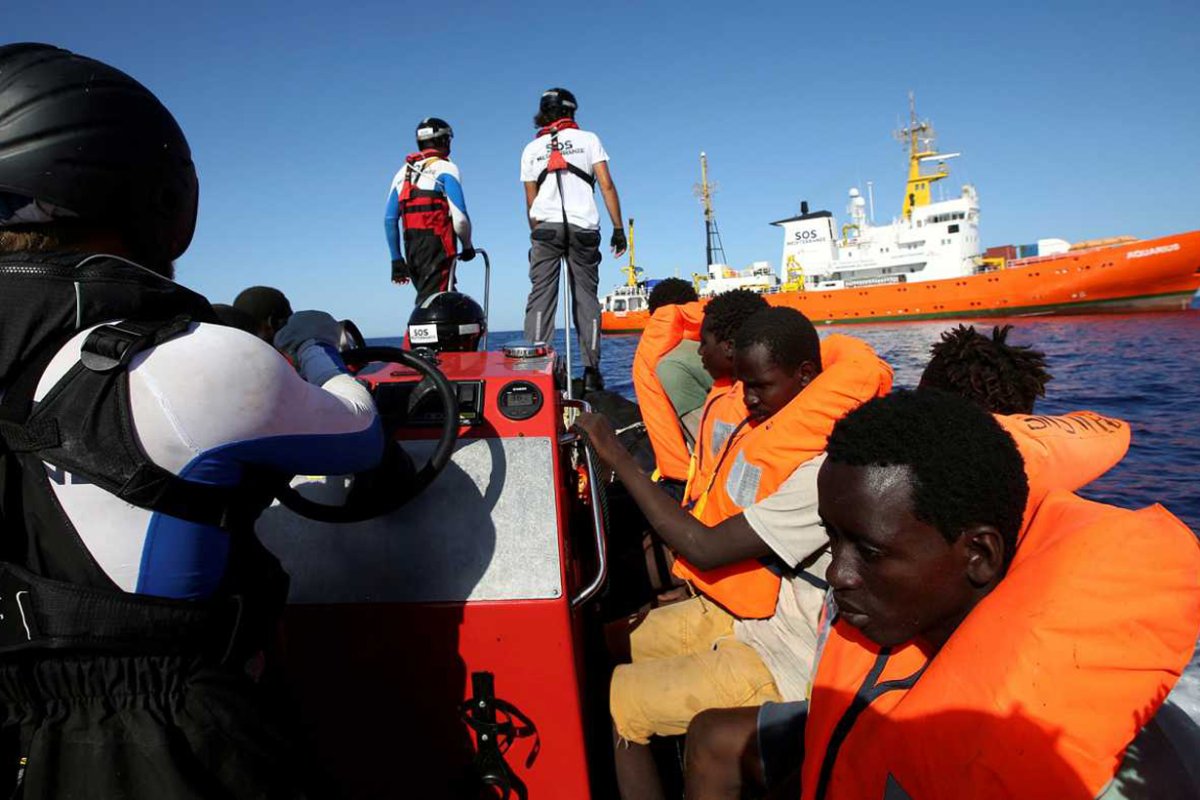 De fondo, Aquarius, el barco lleno de inmigrantes